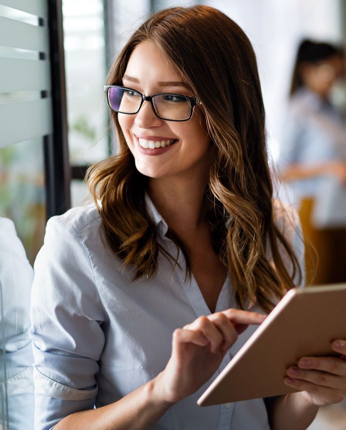 Smiling woman in glasses using a tablet in an office