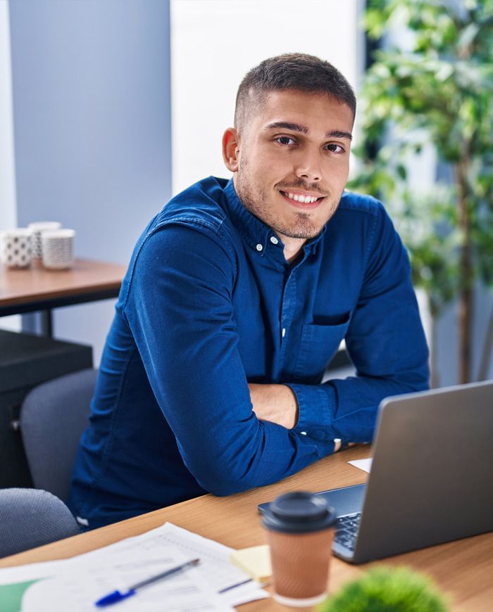 Smiling young man working at a laptop in an office