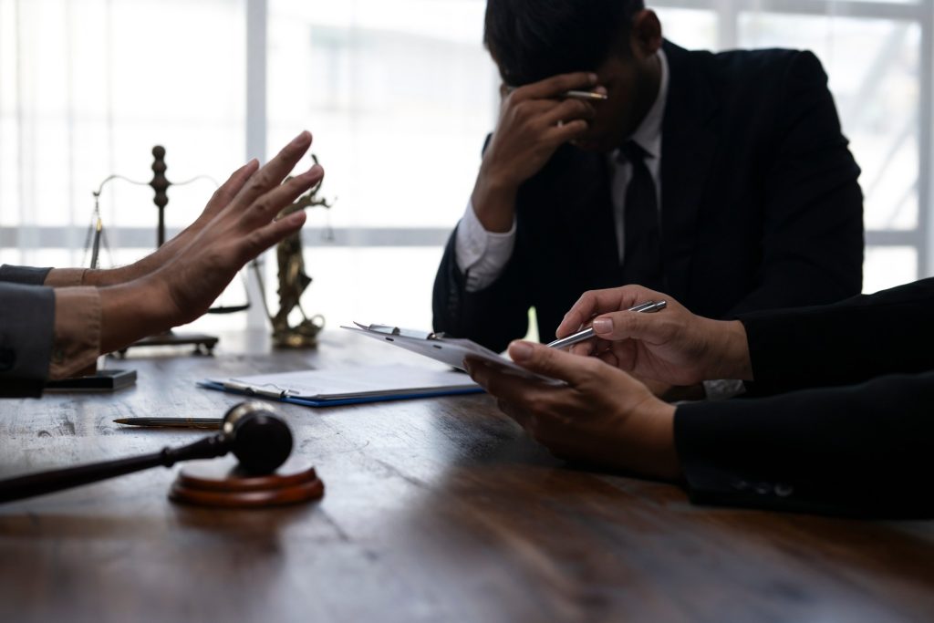 Stressed man in a legal consultation with scales and gavel on the desk